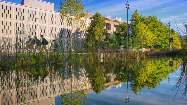 Reflective pond with pedestrians and building behind